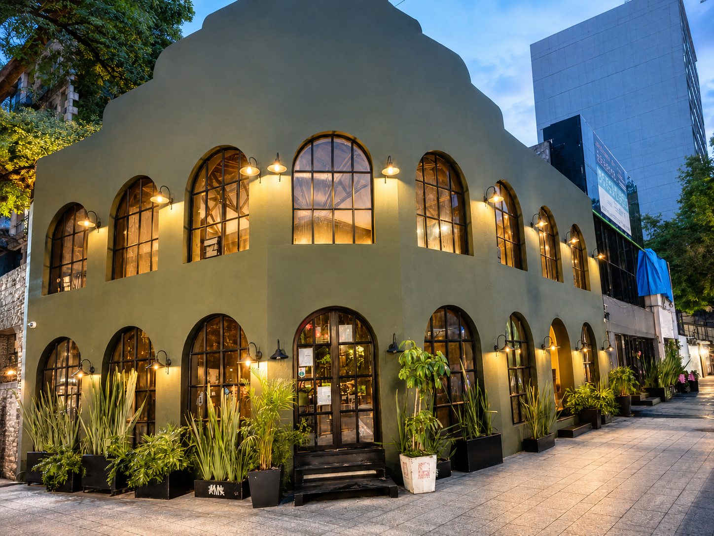 The arched, olive-green facade of JÄGËR in Polanco, glowing warm at dusk