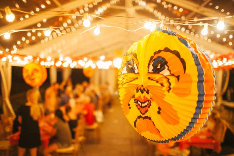 Glowing paper crayfish lanterns strung above a late-summer party tent