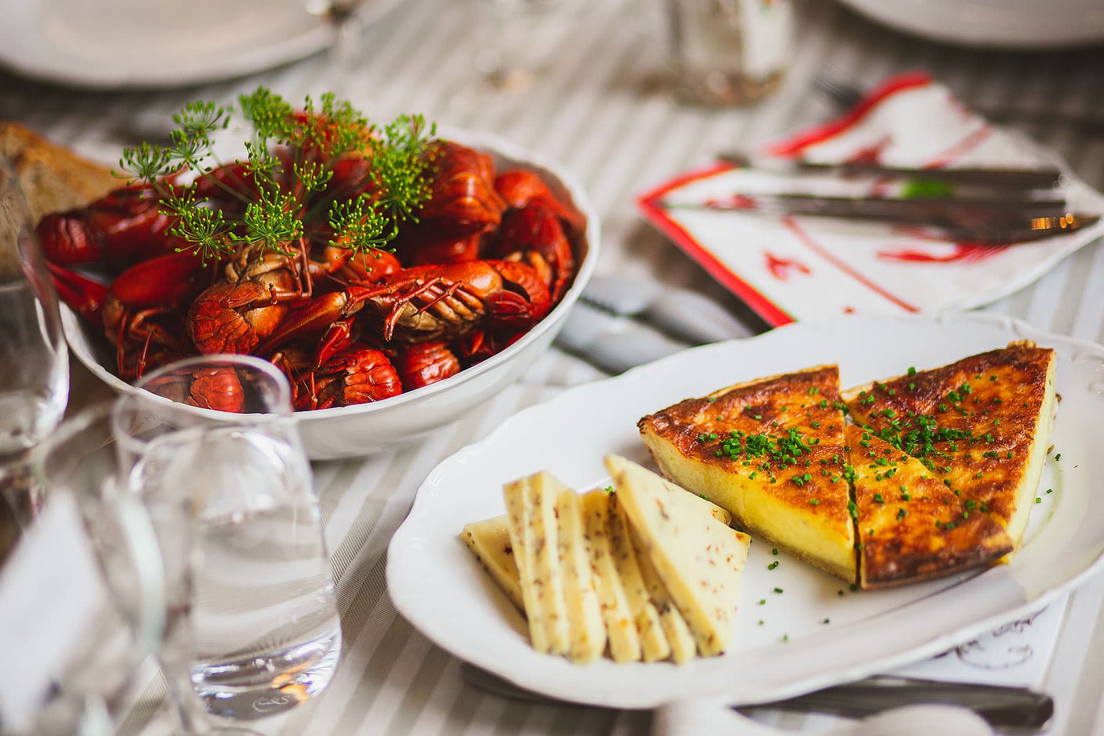 A platter of dill-garnished Swedish crayfish beside aquavit and a glowing moon lantern